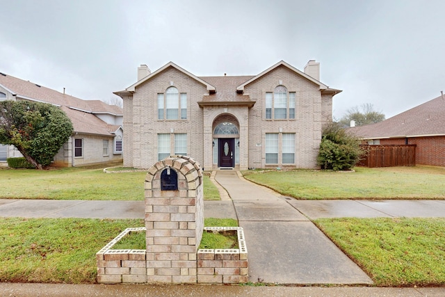 traditional home featuring a front yard, brick siding, and a chimney