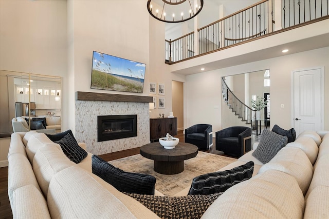 living area with a fireplace, an inviting chandelier, wood finished floors, baseboards, and stairs