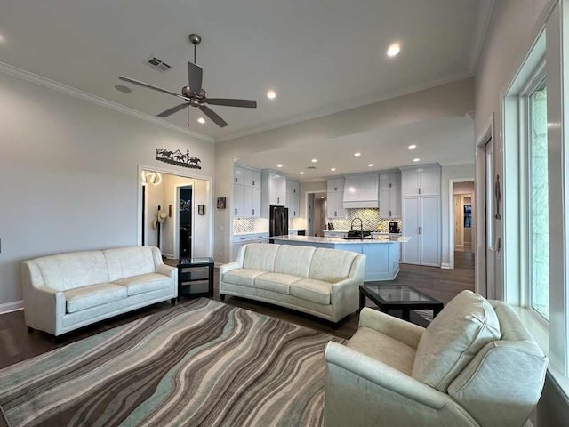 living area featuring visible vents, ornamental molding, ceiling fan, dark wood-type flooring, and recessed lighting