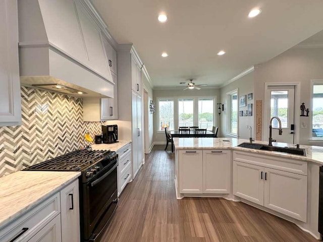 kitchen with black gas range, custom range hood, a sink, and crown molding