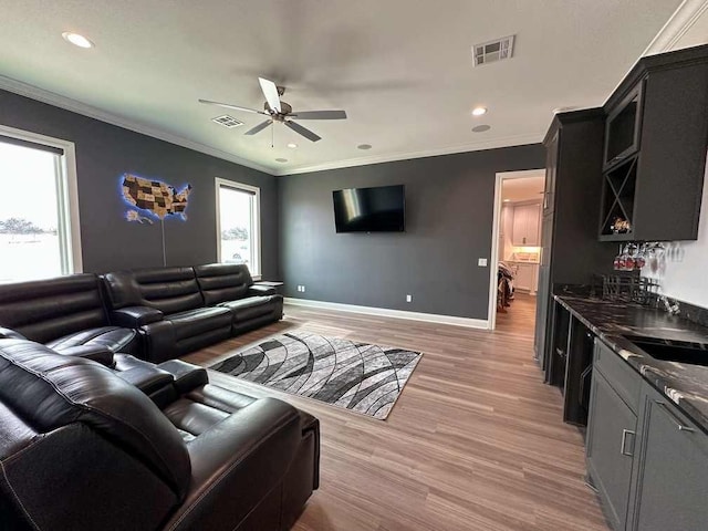 living area with baseboards, a ceiling fan, light wood-style flooring, and visible vents