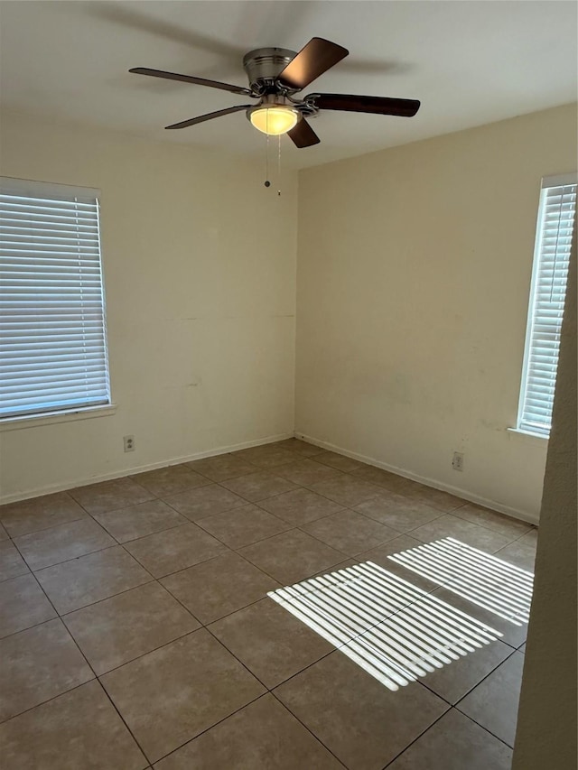 spare room with light tile patterned floors, ceiling fan, and baseboards