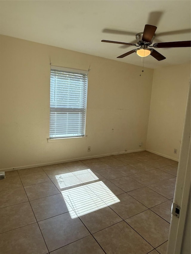 empty room featuring baseboards, a ceiling fan, and light tile patterned flooring