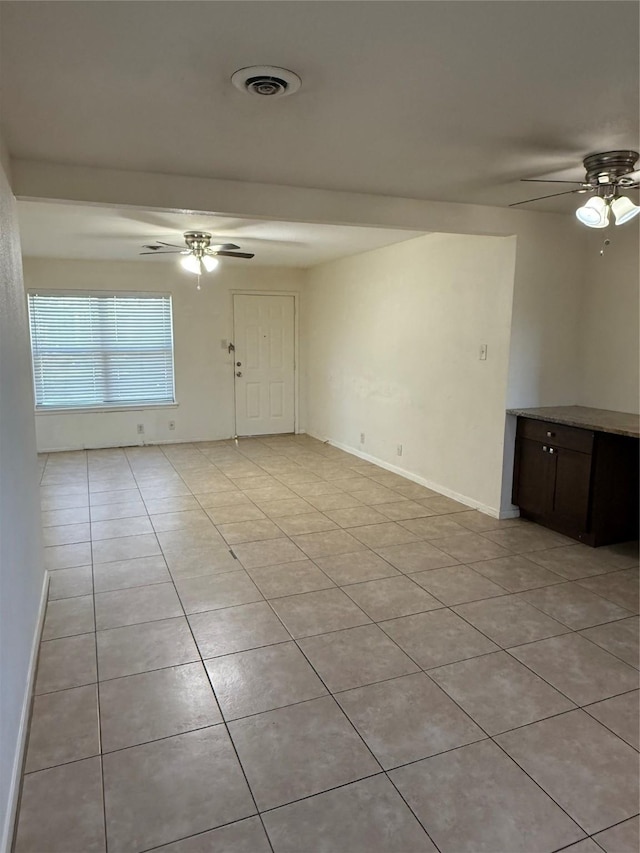 empty room with light tile patterned floors, baseboards, visible vents, and a ceiling fan