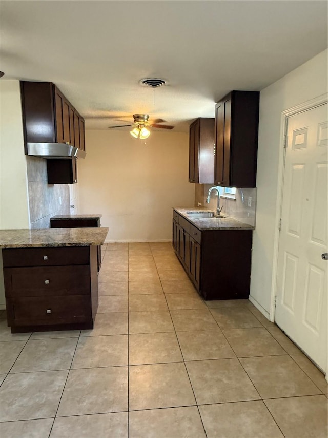 kitchen with light stone counters, visible vents, light tile patterned flooring, a sink, and dark brown cabinetry