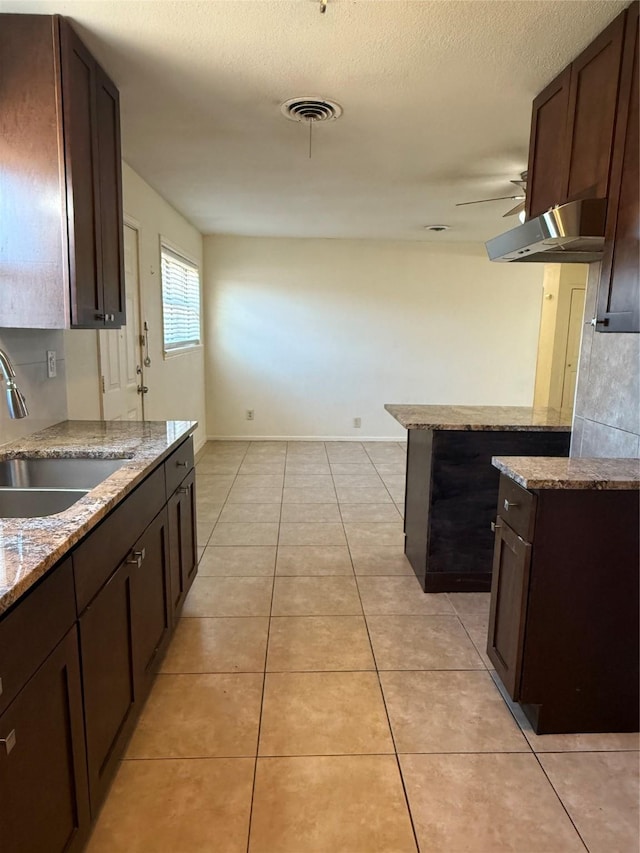 kitchen featuring light tile patterned floors, ceiling fan, a sink, visible vents, and light stone countertops