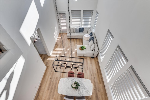 living room with a high ceiling, light wood-style flooring, and baseboards