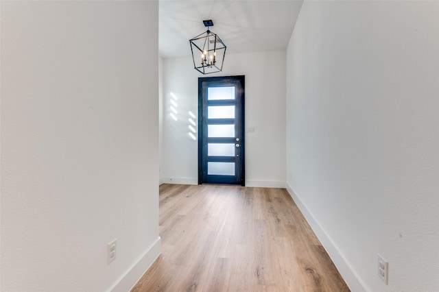 entryway featuring a chandelier, light wood-style flooring, and baseboards