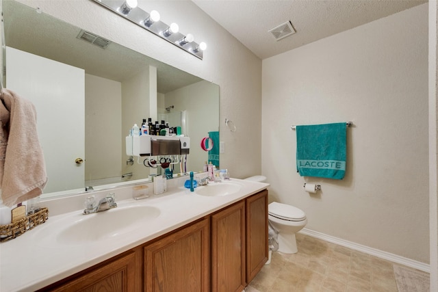 bathroom featuring toilet, double vanity, a sink, and visible vents