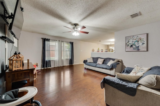 living area with visible vents, ceiling fan, a textured ceiling, and wood finished floors