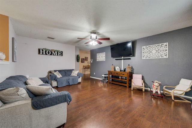 living room with baseboards, visible vents, ceiling fan, dark wood-type flooring, and a textured ceiling