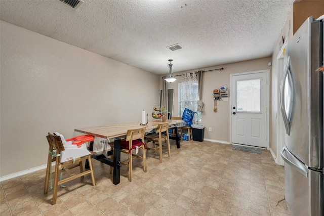 dining room with a textured ceiling, visible vents, and baseboards