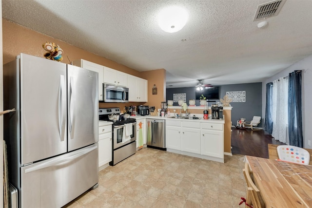 kitchen featuring stainless steel appliances, light countertops, visible vents, white cabinetry, and a sink