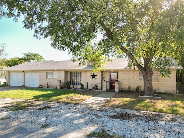 ranch-style house featuring a front lawn, an attached garage, brick siding, and a fenced front yard