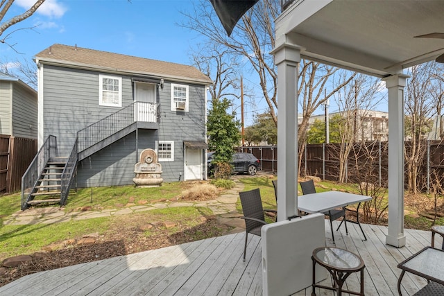 wooden terrace featuring outdoor dining area, fence, and stairs