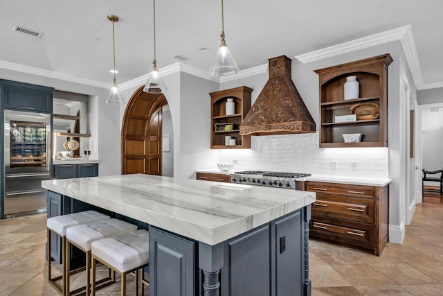 kitchen featuring high quality fridge, a kitchen island, light stone countertops, premium range hood, and open shelves