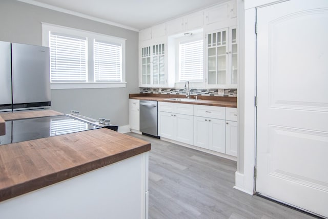 kitchen with wooden counters, a sink, white cabinetry, and stainless steel appliances