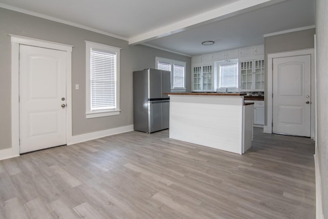 kitchen with baseboards, light wood-style flooring, freestanding refrigerator, and crown molding