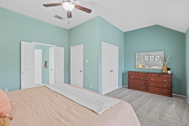 carpeted bedroom with vaulted ceiling, a closet, visible vents, and a ceiling fan