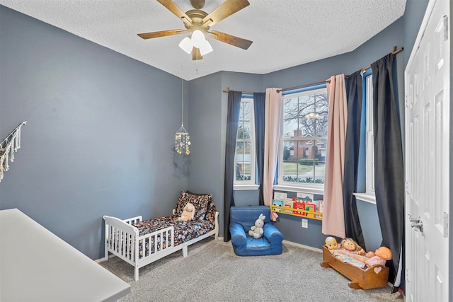 carpeted bedroom featuring a textured ceiling, ceiling fan, and baseboards