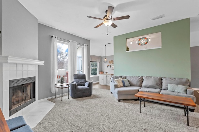 living area with ceiling fan, visible vents, baseboards, and a tile fireplace