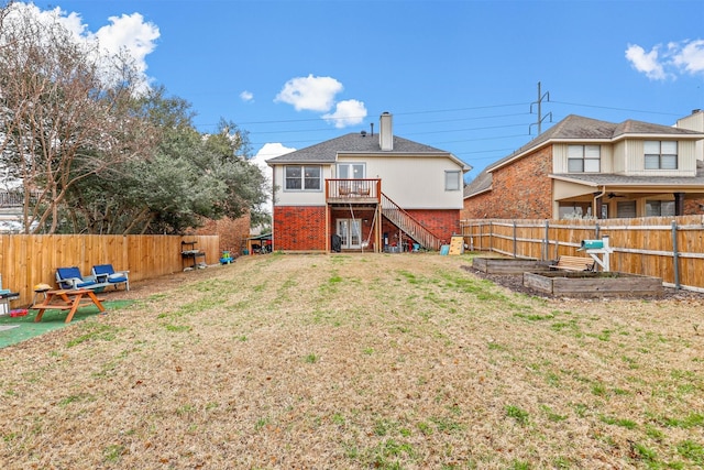 back of house featuring stairs, a yard, brick siding, and a fenced backyard