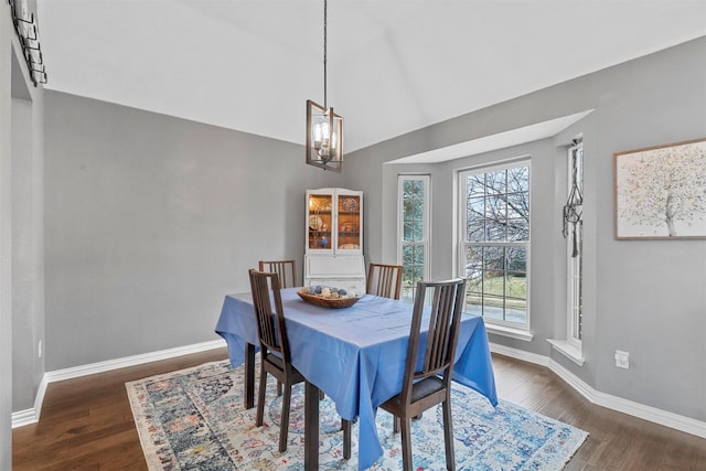 dining space with lofted ceiling, dark wood-style flooring, baseboards, and an inviting chandelier