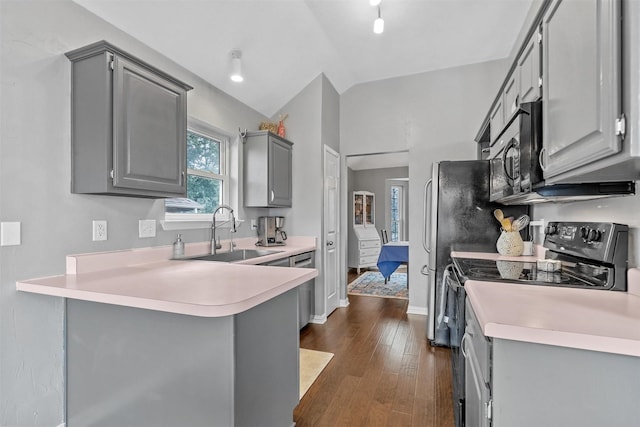 kitchen featuring light countertops, a peninsula, a sink, and gray cabinetry