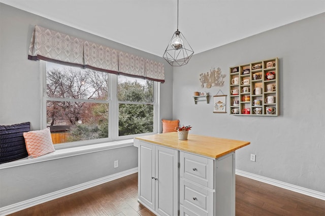 dining space featuring dark wood finished floors and baseboards