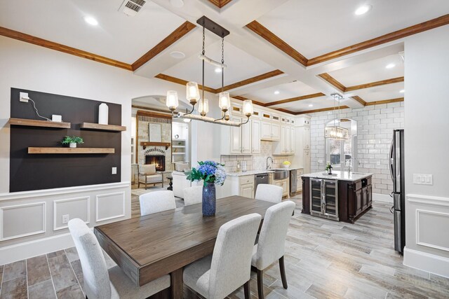 7101 Bridges Ave, Richland Hills, TX 76118 - dining space featuring beam ceiling, a fireplace, visible vents, a decorative wall, and light wood-style floors