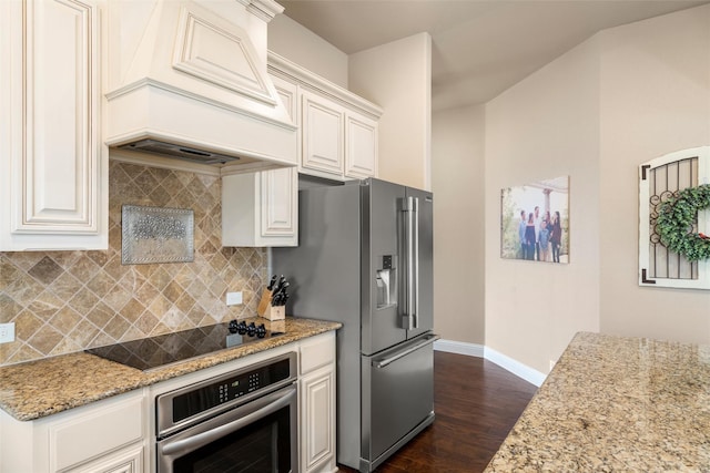 kitchen featuring appliances with stainless steel finishes, white cabinets, premium range hood, and light stone counters