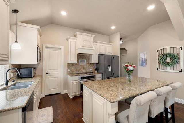 kitchen with hanging light fixtures, white cabinetry, stainless steel appliances, and a sink