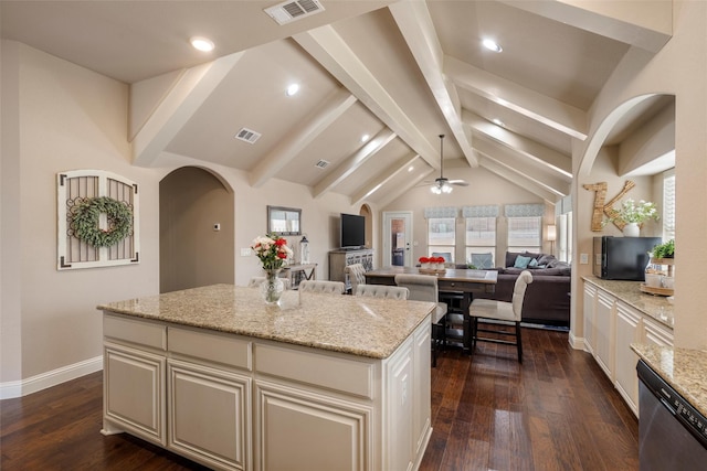 kitchen featuring light stone countertops, visible vents, open floor plan, a center island, and dishwasher