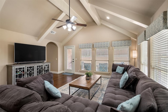 living area featuring baseboards, arched walkways, a ceiling fan, wood finished floors, and vaulted ceiling with beams