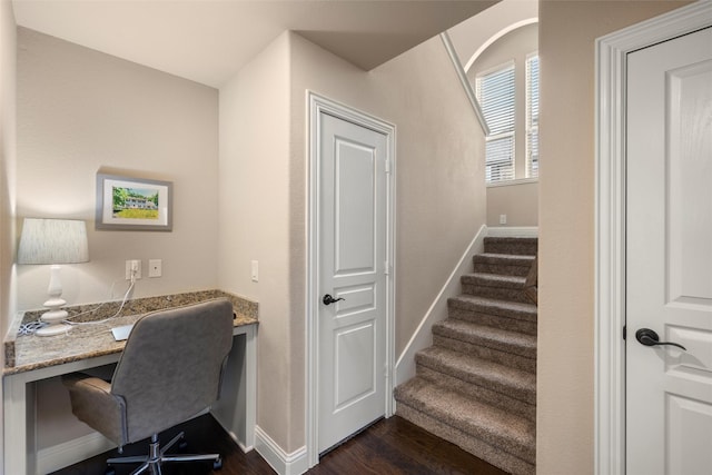 office space featuring dark wood-type flooring, built in study area, and baseboards