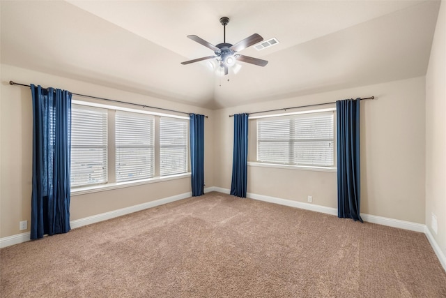 carpeted empty room featuring plenty of natural light, visible vents, vaulted ceiling, and baseboards