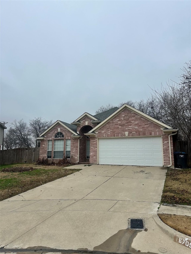 single story home with driveway, an attached garage, fence, and brick siding