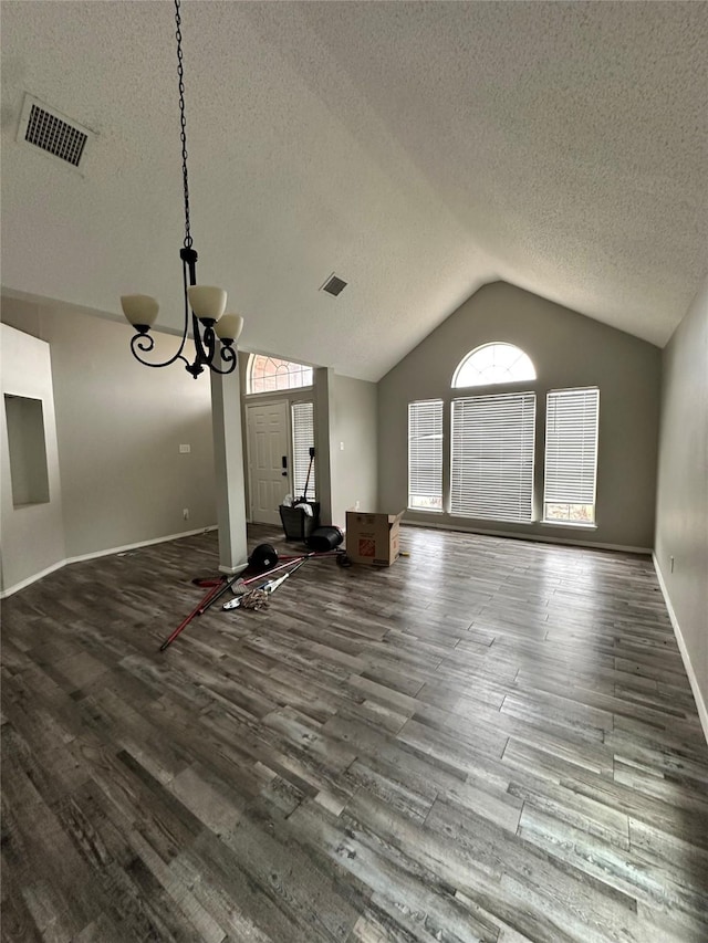 unfurnished living room featuring a notable chandelier, visible vents, vaulted ceiling, and dark wood-type flooring