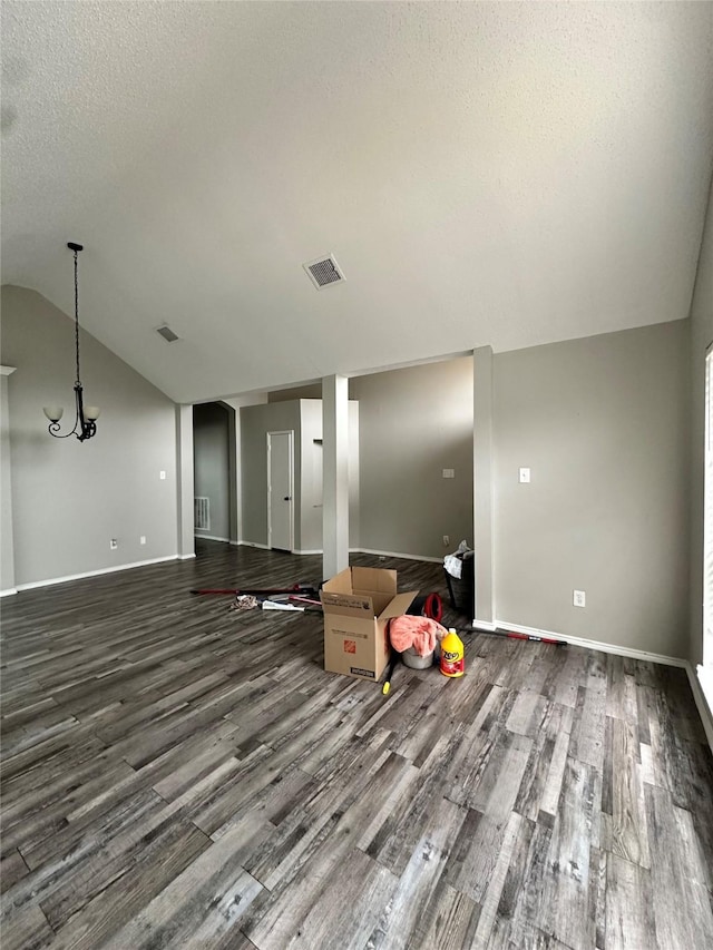 unfurnished living room with lofted ceiling, a textured ceiling, wood finished floors, and visible vents