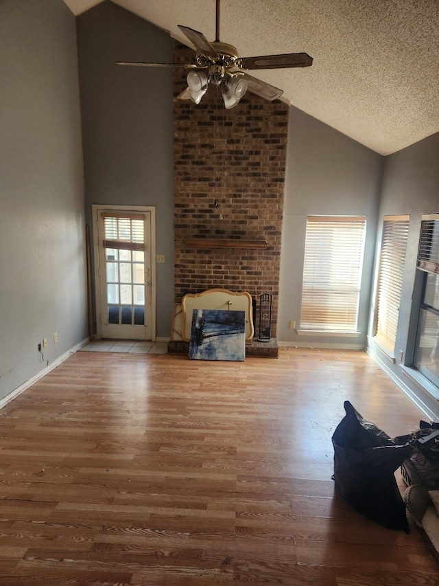 unfurnished living room with a fireplace, a ceiling fan, a textured ceiling, wood finished floors, and baseboards