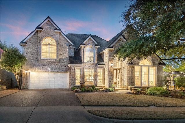 french provincial home featuring brick siding, driveway, and an attached garage