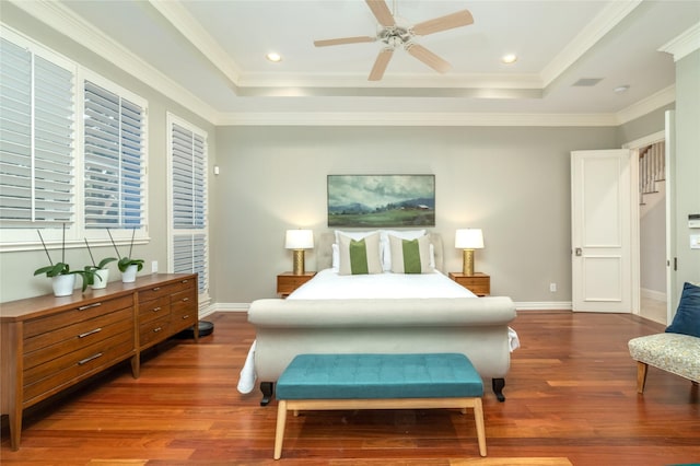 bedroom featuring a tray ceiling, dark wood-style flooring, and ornamental molding