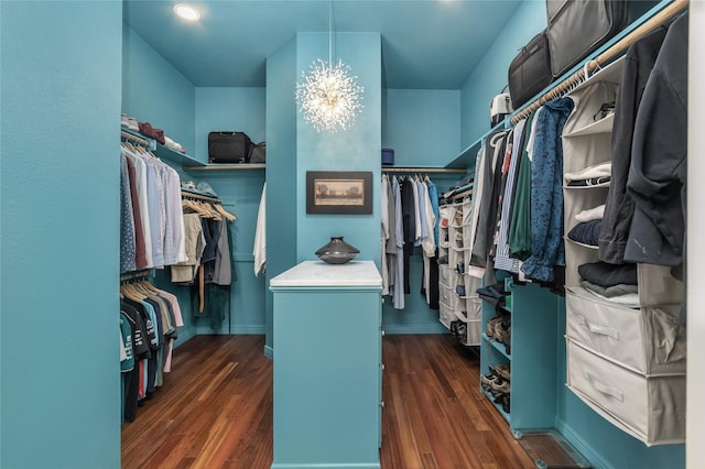 spacious closet featuring a notable chandelier and dark wood-type flooring