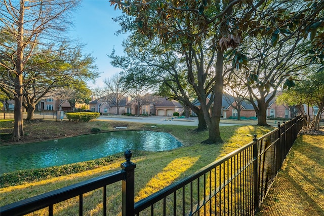 view of property's community with a lawn, a water view, fence, and a residential view