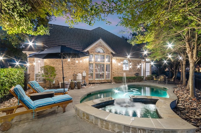 pool at dusk featuring an outdoor pool, a patio, and an in ground hot tub