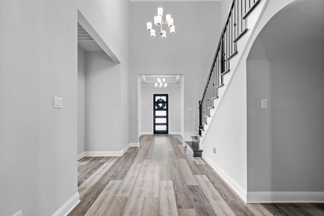 entryway with arched walkways, baseboards, an inviting chandelier, and wood finished floors