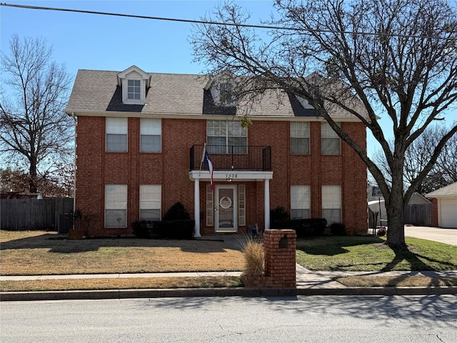 view of front of property with a shingled roof, fence, a front lawn, and brick siding