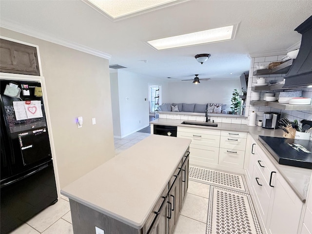 kitchen featuring ornamental molding, open floor plan, a sink, a peninsula, and black appliances