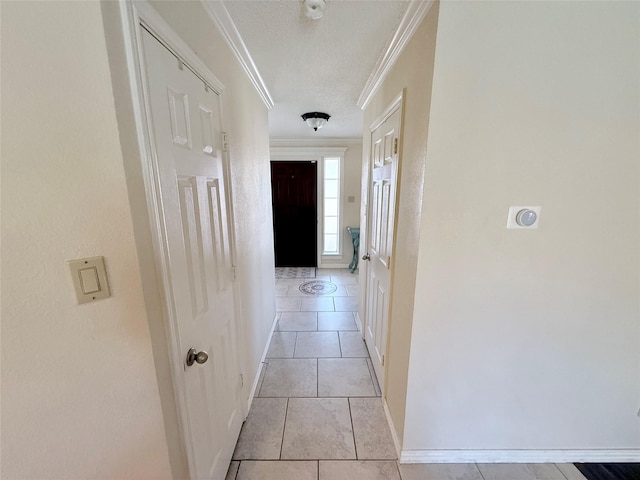 hallway featuring light tile patterned floors, baseboards, and crown molding