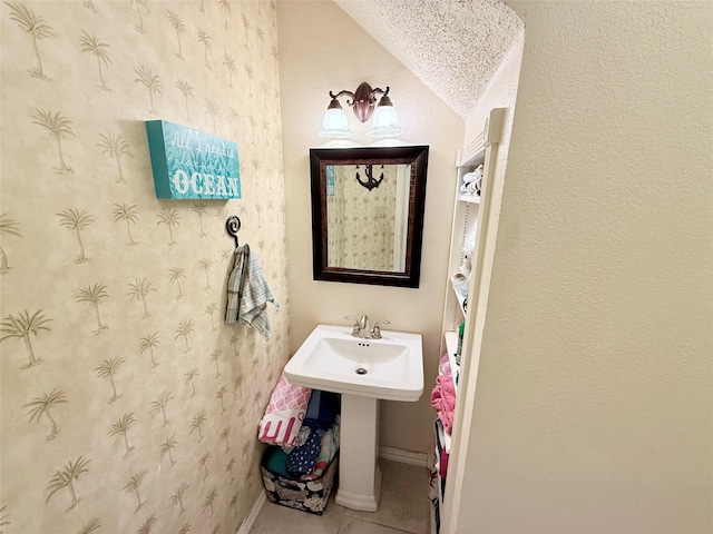 bathroom featuring baseboards, a sink, and tile patterned floors